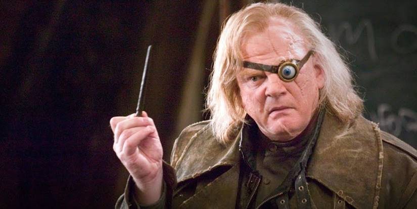 Brendan Gleeson as Mad Eye Moody holds a wand in front of a chalk board in Harry Potter and the Goblet of Fire.