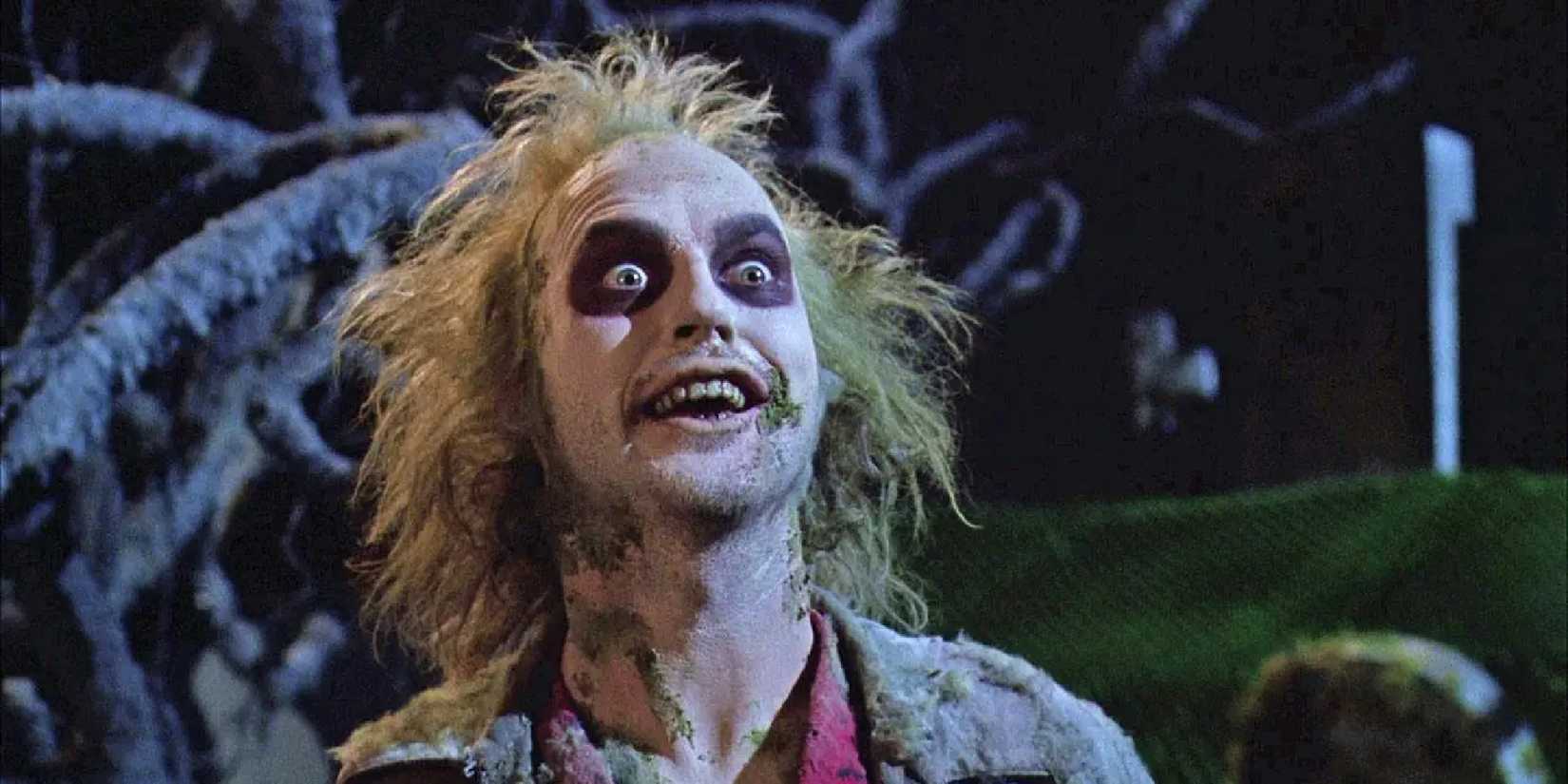 Michael Keaton as Beetlejuice smiling with an unhinged expression in Beetlejuice.