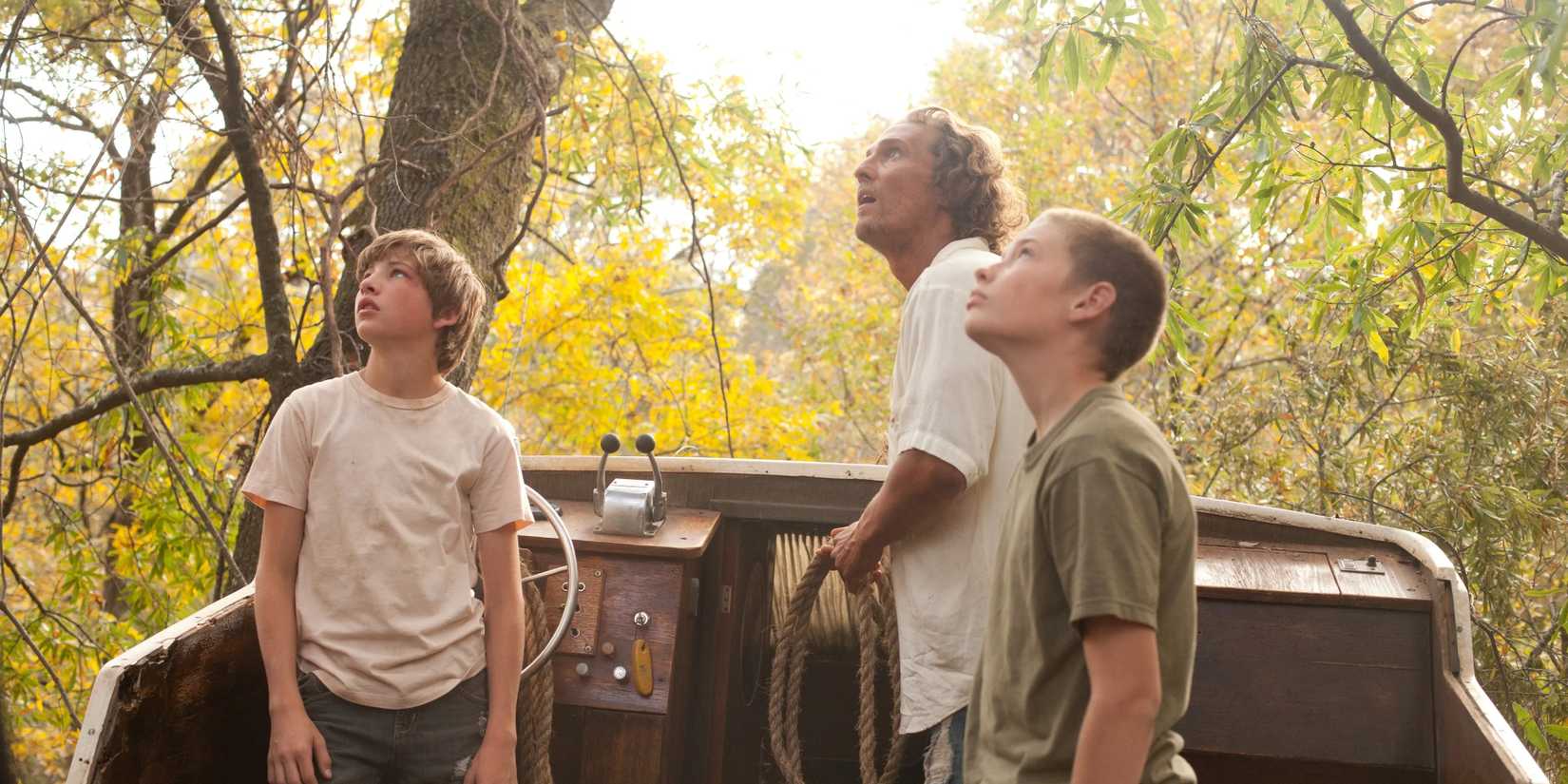 A man and two young boys looking up at something in Mud 2013