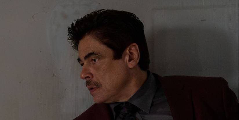 Benicio del Toro, kas stāv pret rāpuļu sienu 