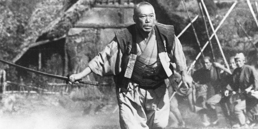 Takashi Shimura holding a sword and moving forward in Seven Samurai.