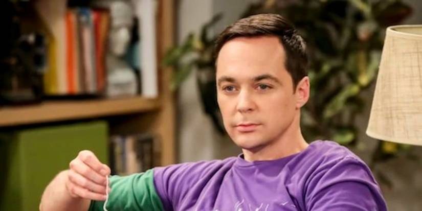 Jim Parsons as Sheldon Cooper sitting on a couch and looking pensive in The Big Bang Theory.