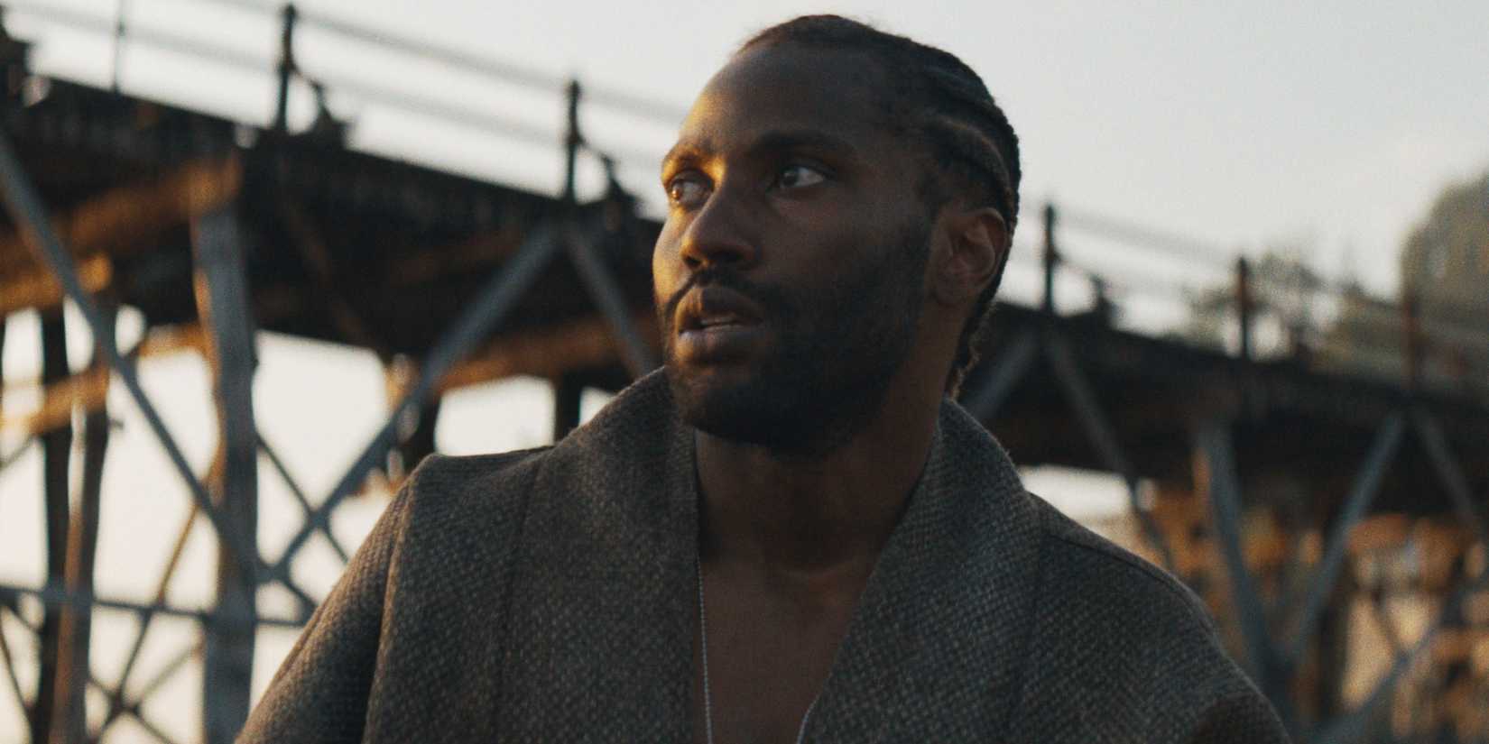 John David Washington as Joshua standing below a bridge in The Creator