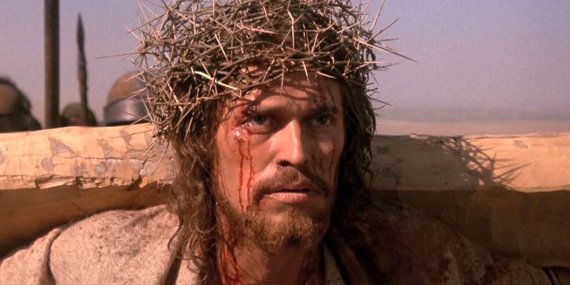 Willem Dafoe as Jesus in The Last Temptation of Christ, wearing a thorn crown and holding the cross