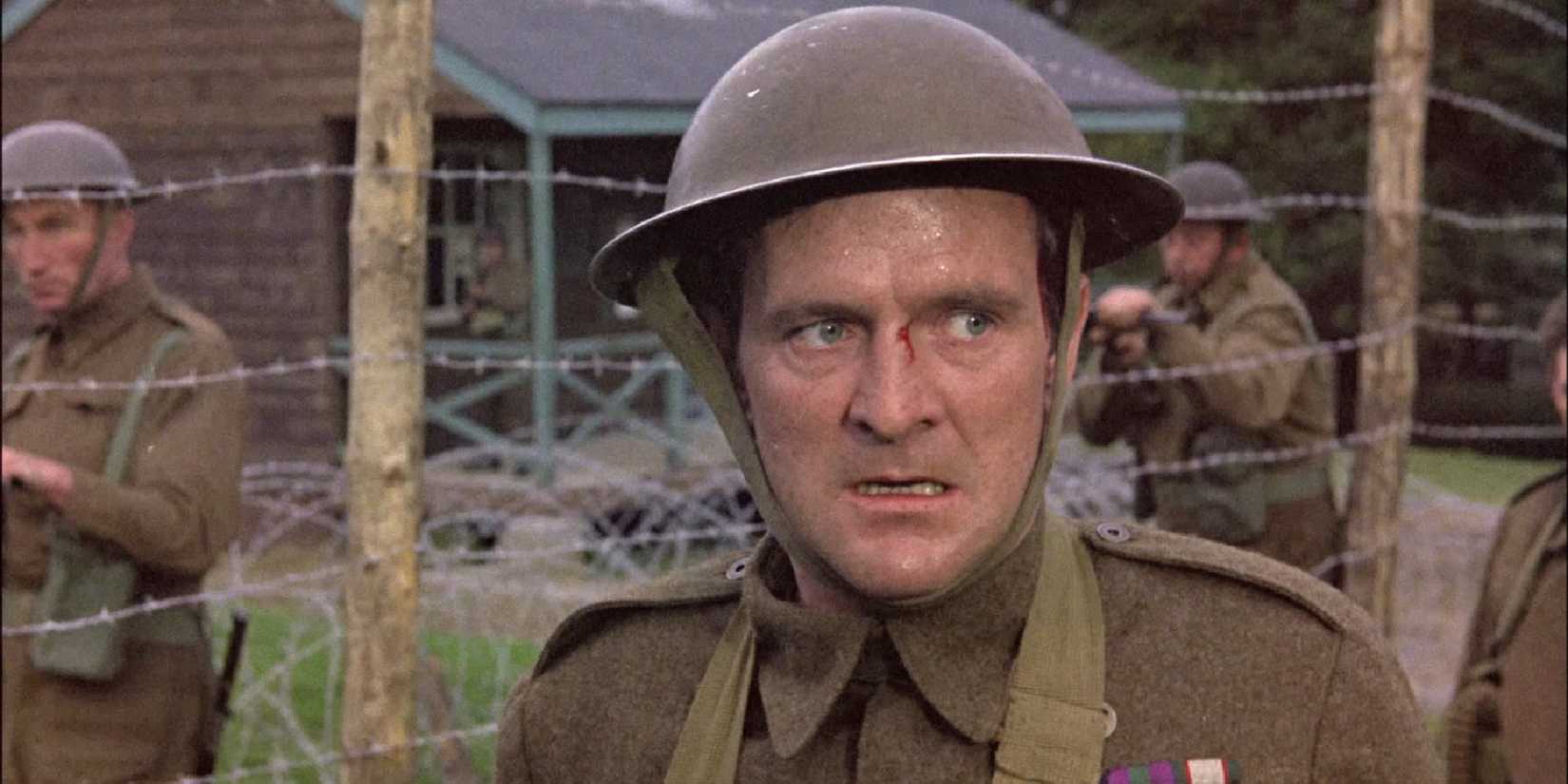 A soldier stands in front of a barbed wire fence with a small wound on his nose in The McKenzie Break.