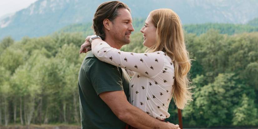 A man and woman embrace in front of forested mountains in Virgin River episode The Long Goodbye.