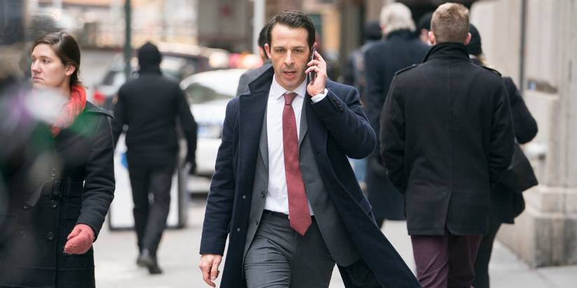 Kendall Roy from Succession walking down the street in a peacock and suit on the phone looking angry.