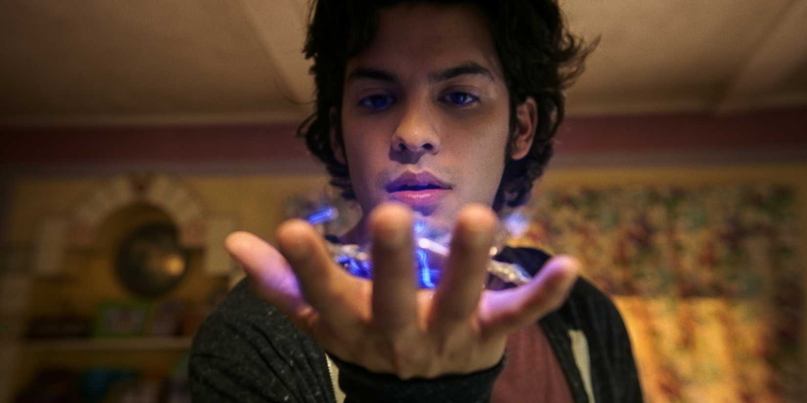 Xolo Maridueña as Jaime Reyes holding the scarab before it implants itself in him in Blue Beetle