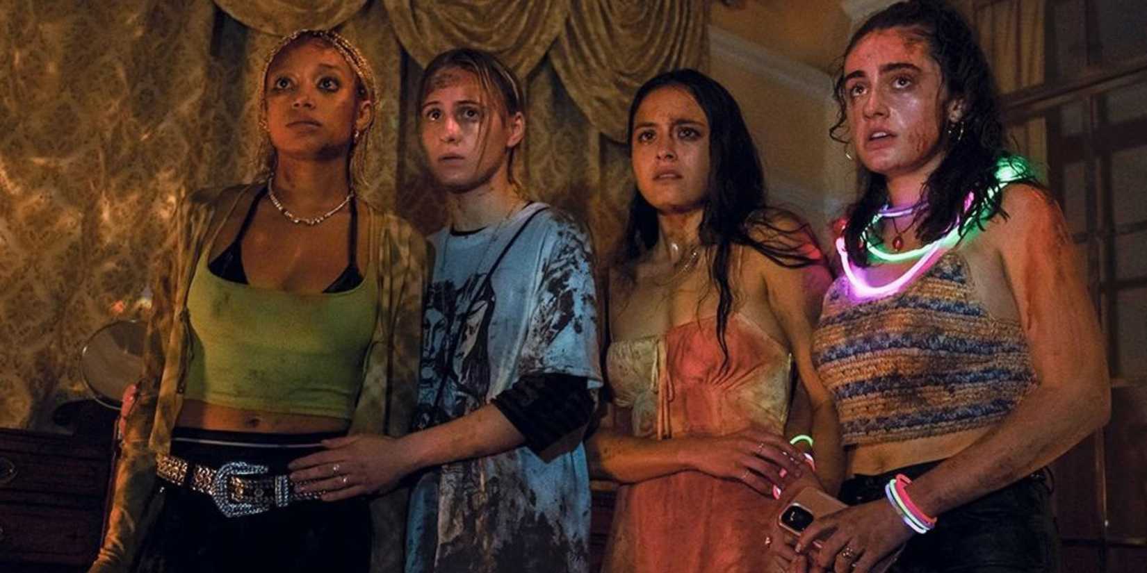 Four wounded friends stand shocked and wear glow sticks around their necks in Bodies Bodies Bodies.