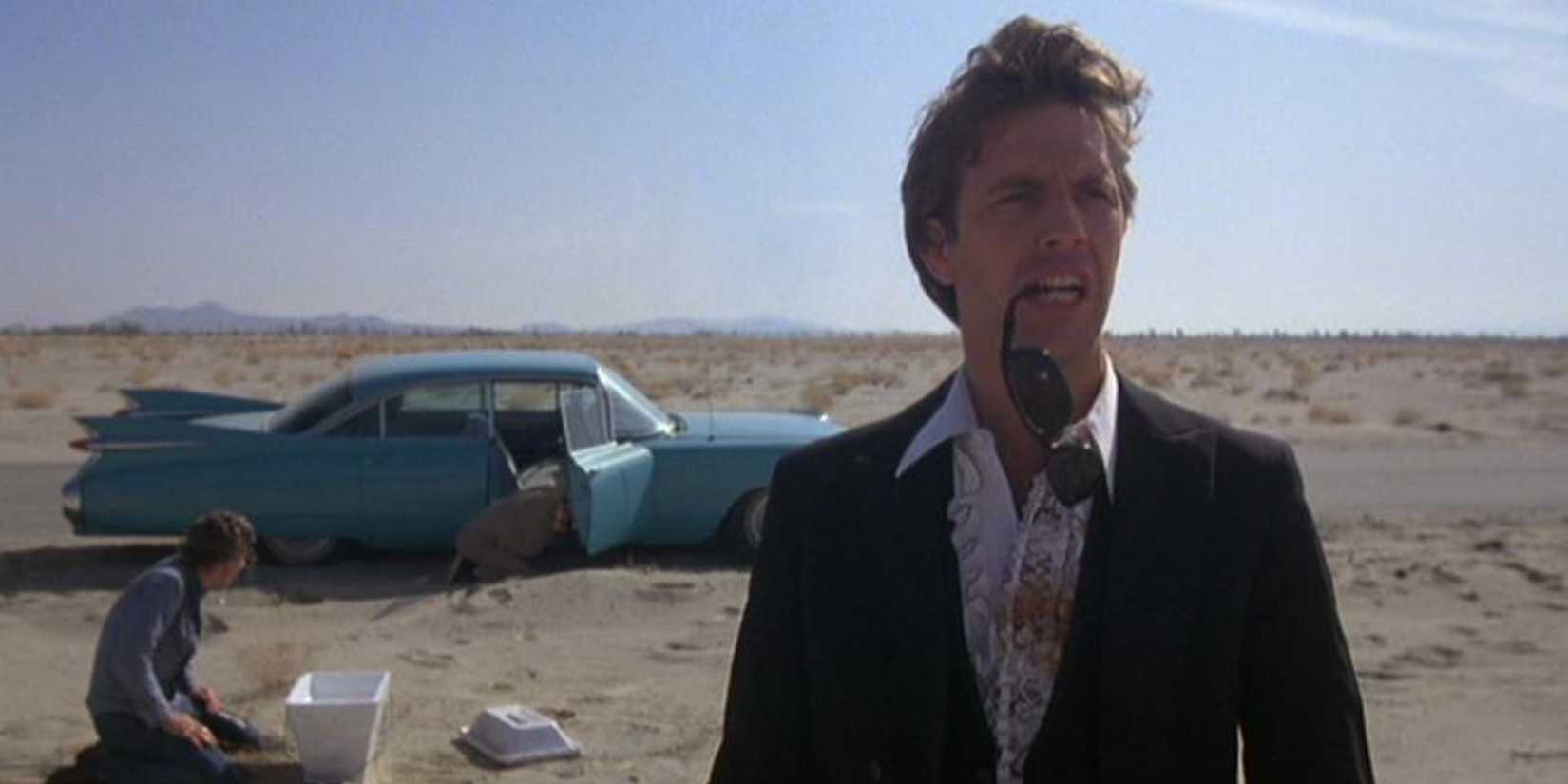 A man in the desert with sunglasses hanging from his mouth in Fandango - 1985