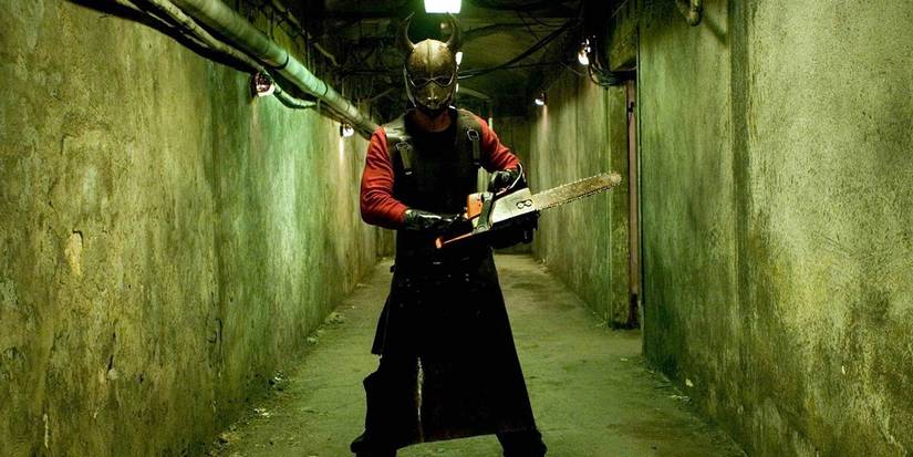 A villain wears a mask while holding a chainsaw in 'Hostel'