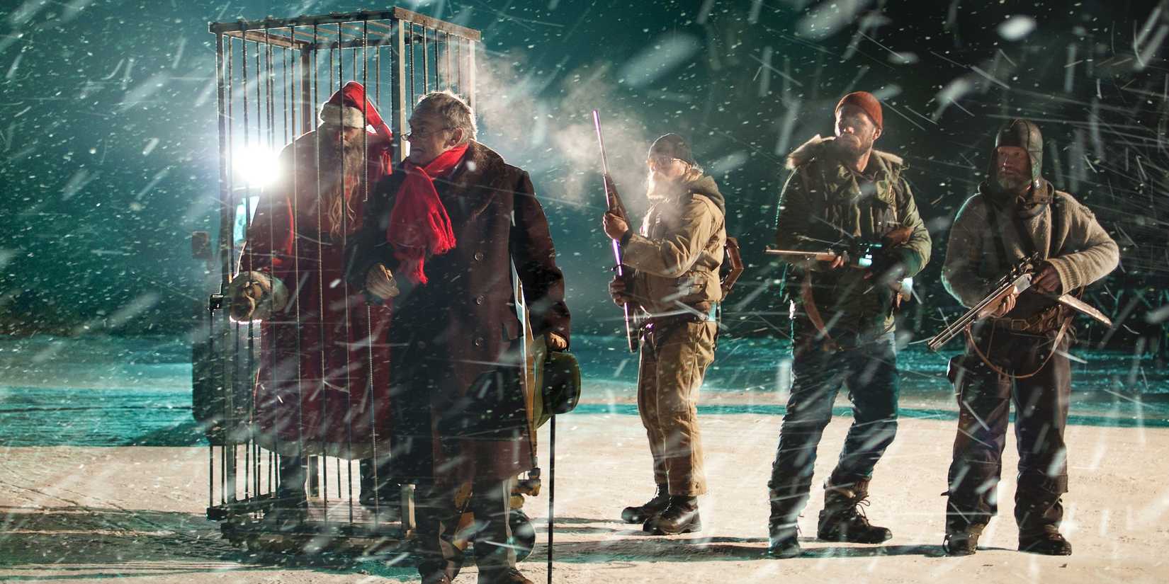 A group of men guard a caged Santa in a snowy landscape