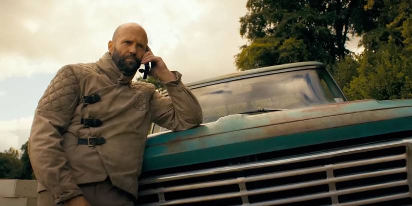 Jason Statham on the phone, leaning against a truck in 'The Beekeeper'