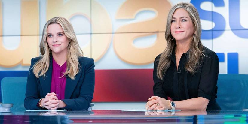 Jennifer Aniston and Reese Witherspoon sitting at a newsdesk in The Morning Show