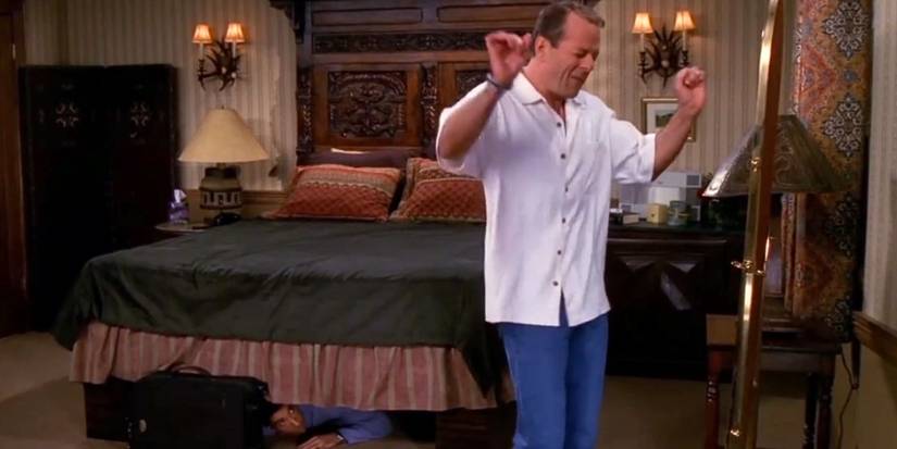 Paul (Bruce Willis) dancing in front of a mirror while Ross (David Schwimmer) hides under the bed in Friends