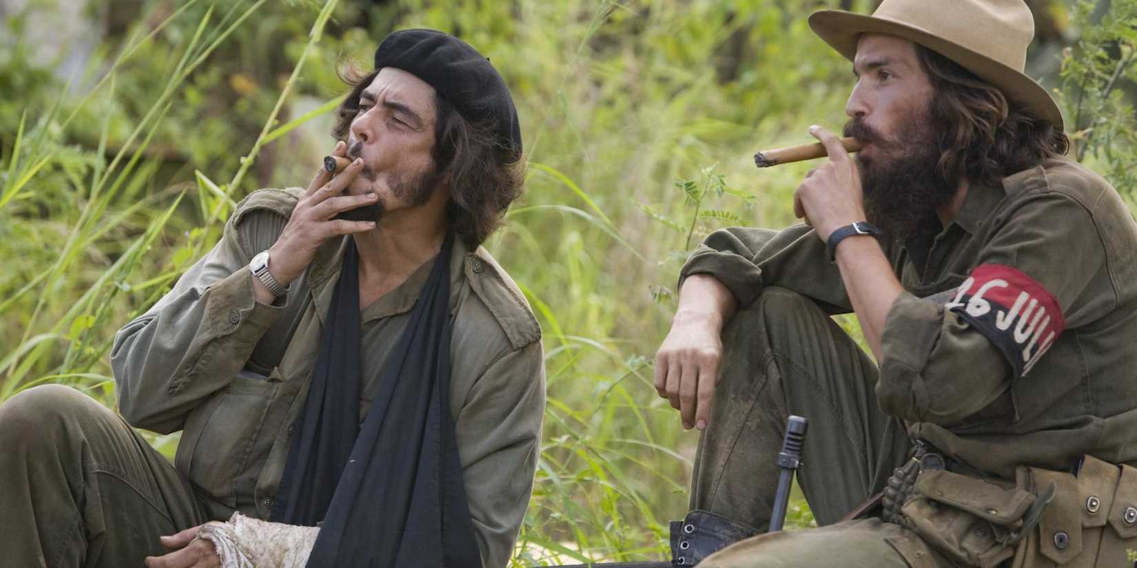 Two men smoke cigars outdoors in a still from 'Che: Part One' (2008).