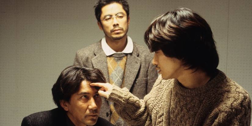 A man touching another man's forehead in Cure.