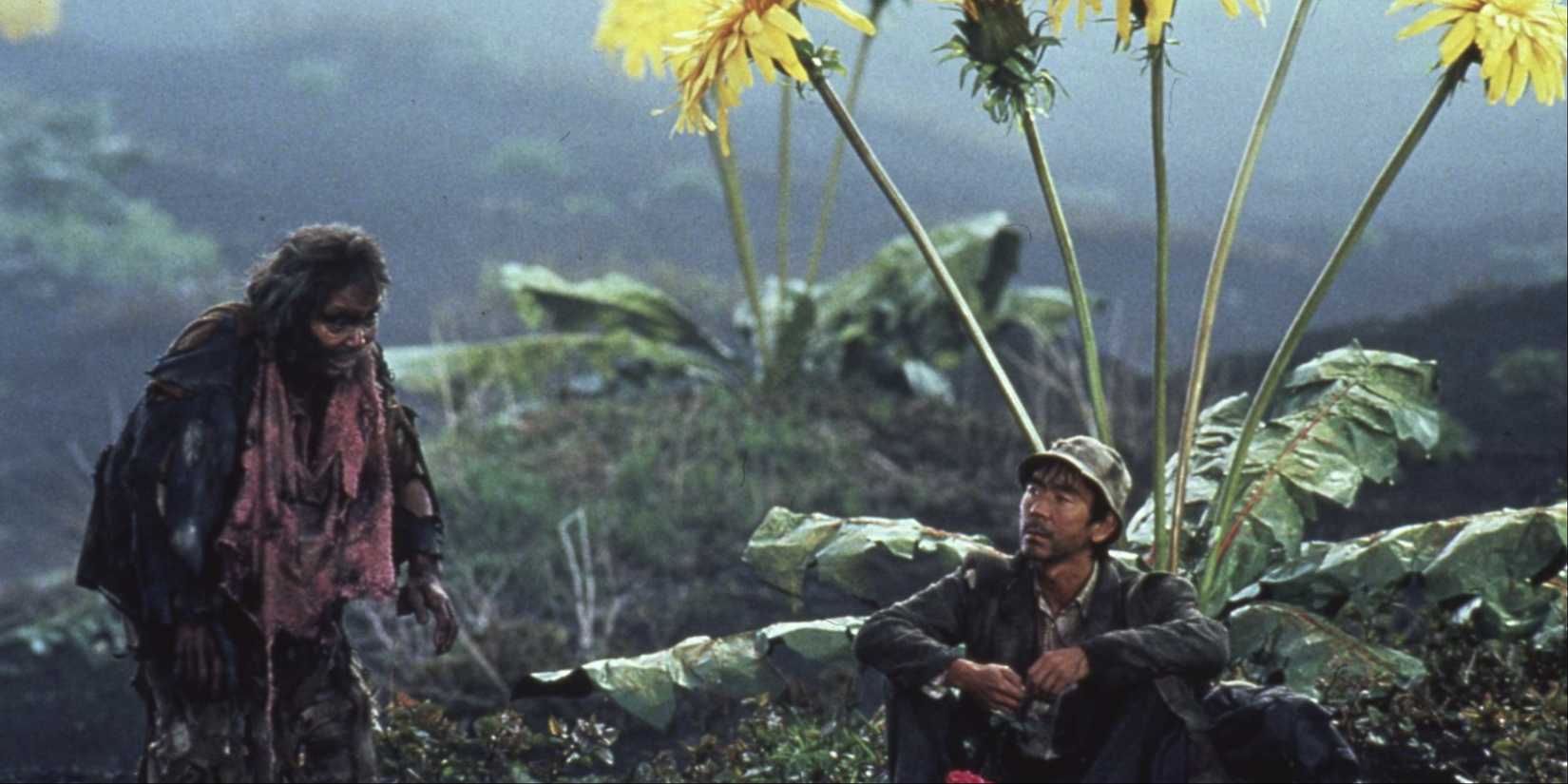 Two people sitting and standing near a large dandelion in Dreams by Akira Kurosawa