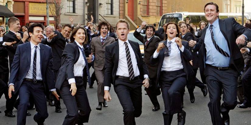 The cast of How I Met Your Mother perform a musical number dressed in suits with an ensemble behind.