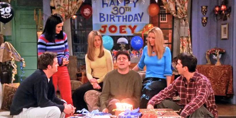 Matthew Perry as Chandler, Jennifer Aniston as Rachel, David Schwimmer as Ross, Courteney Cox as Monica, and Lisa Kudrow as Phoebe standing around Matt LeBlanc as Joey for his 30th birthday in Friends