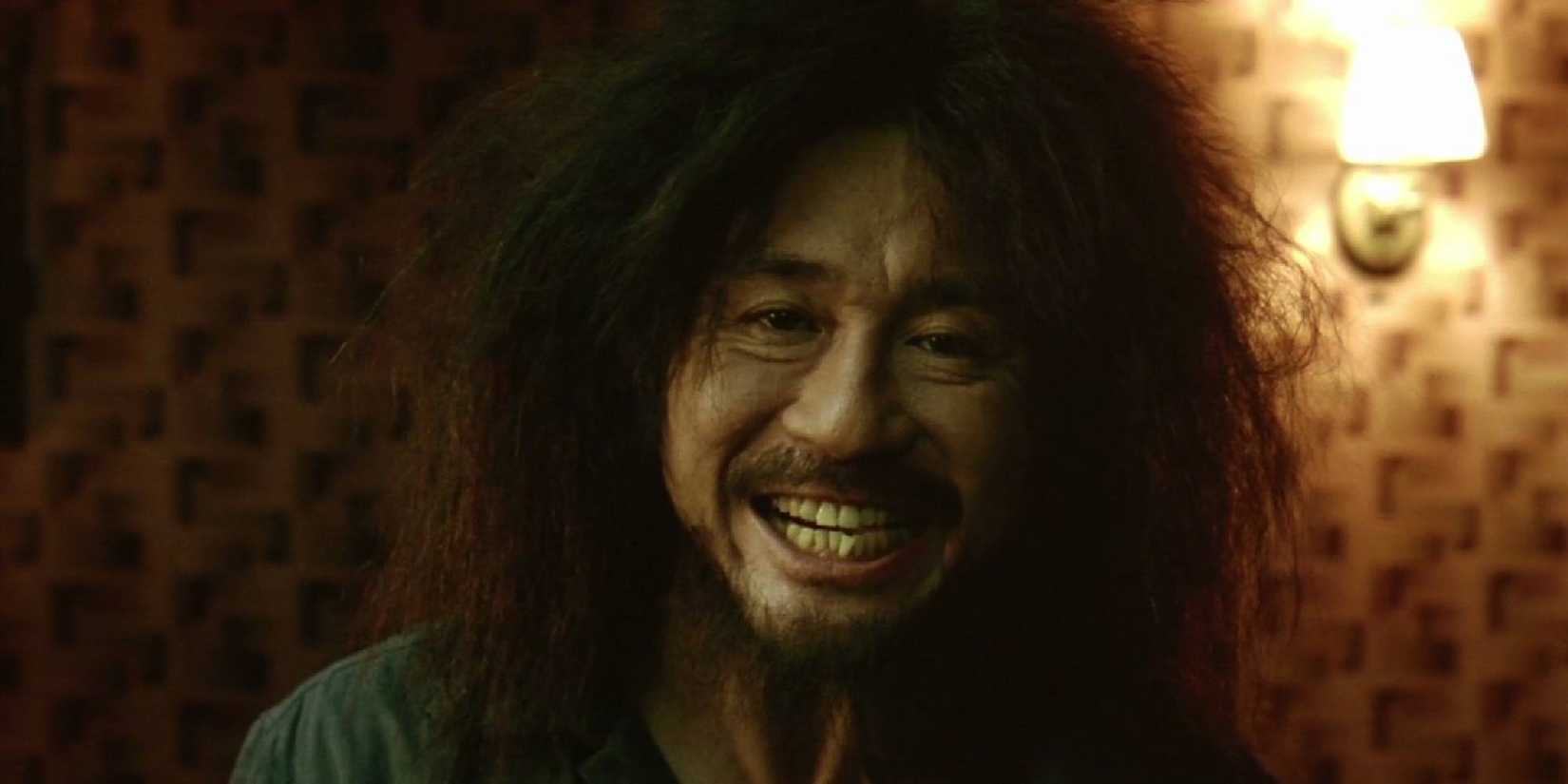 Choi Min-sik in Oldboy smiling hauntingly in Oldboy.