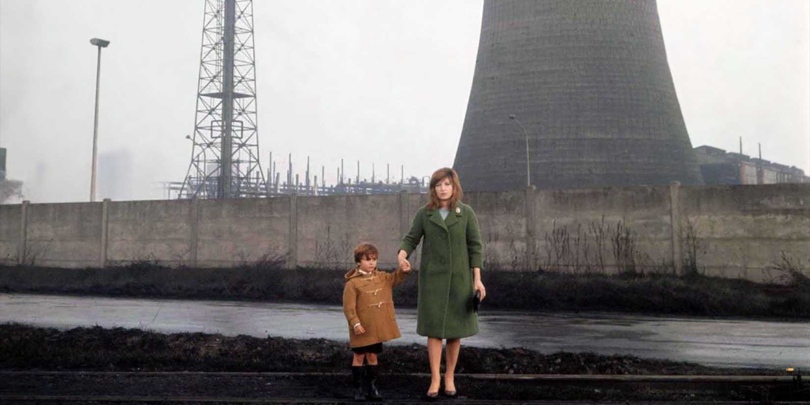 A woman holding a child's hand in Red Desert