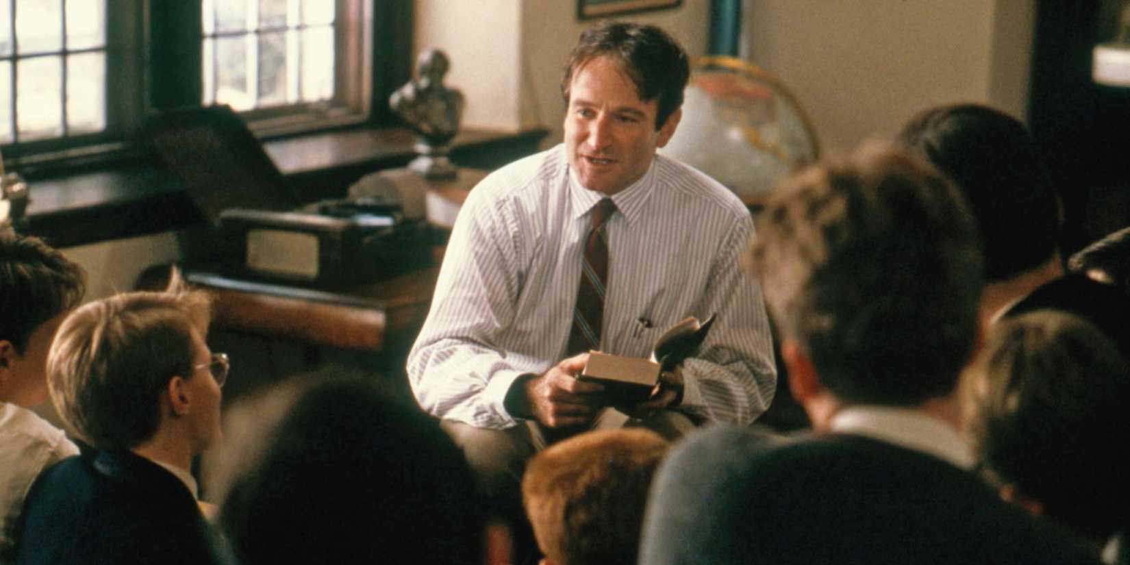 Robin Williams talking to students and holding a book in Dead Poets Society