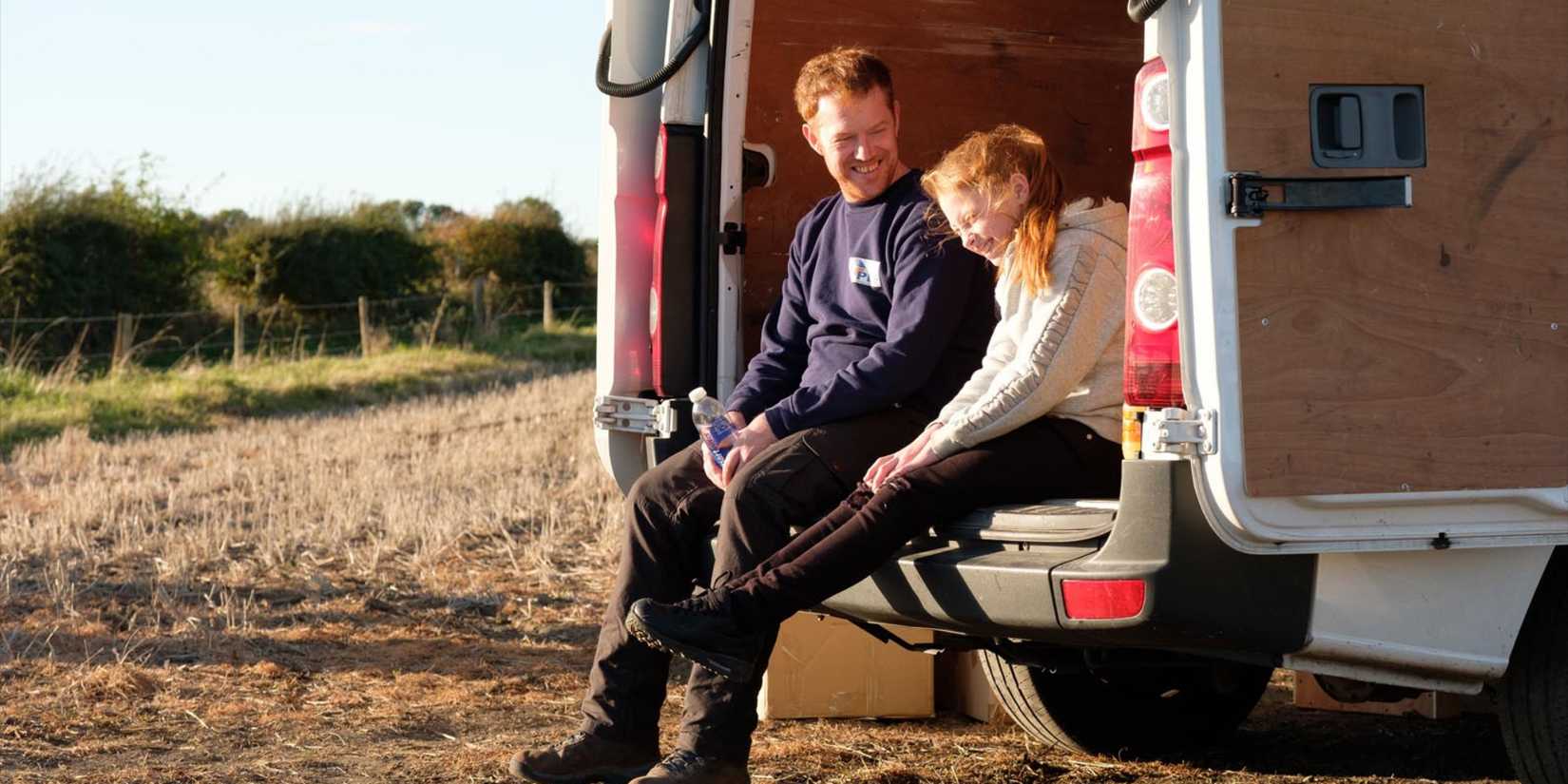 A father and daughter sitting in the back of a van in Sorry We Missed You