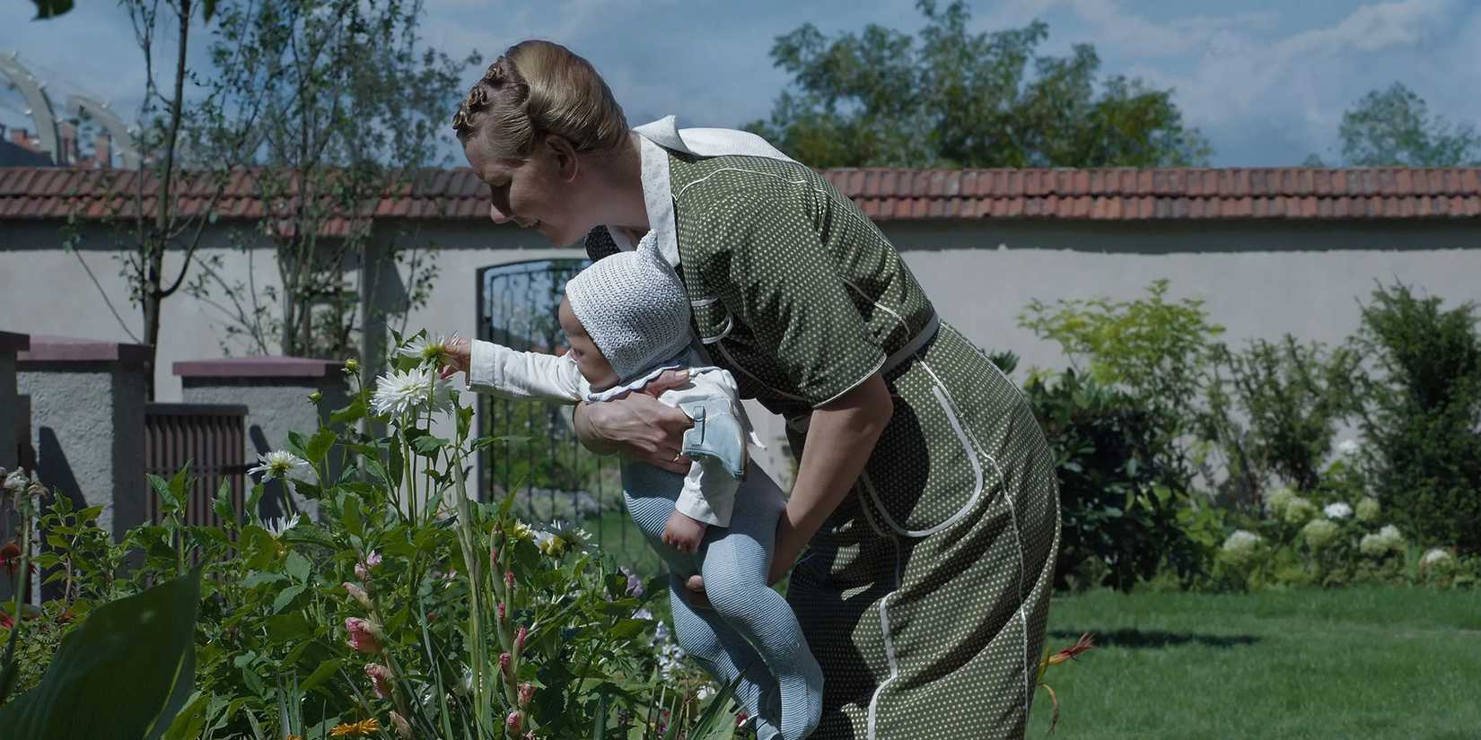 Sandra Hüller as Hedwig Höss picks flowers in her garden with her baby in The Zone of Interest