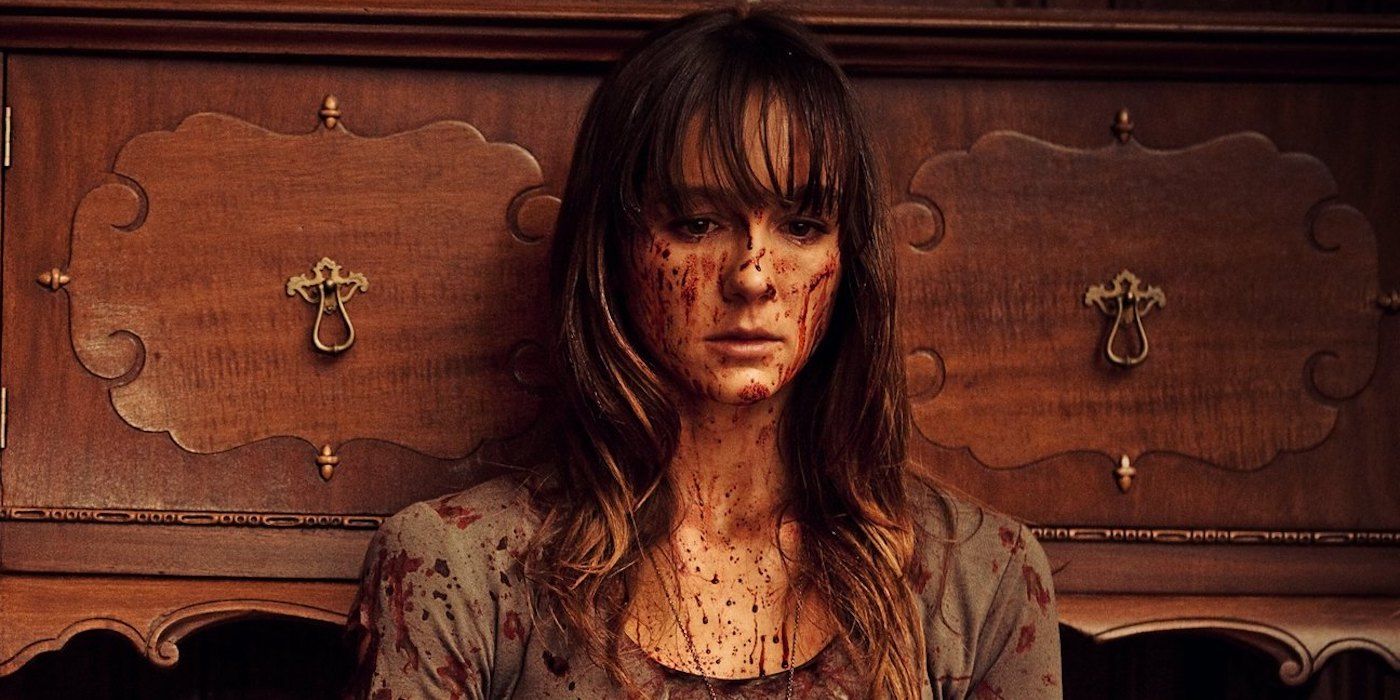 A young woman with blood on her face looking sad in You're Next Film