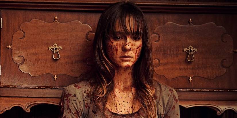 A young woman with blood on her face looking sad in You're Next Film