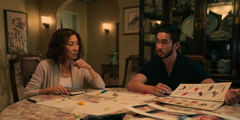 Mama Sun (Michelle Yeoh) and Charles Sun (Justin Chien) sitting at a kitchen table in The Brothers Sun.