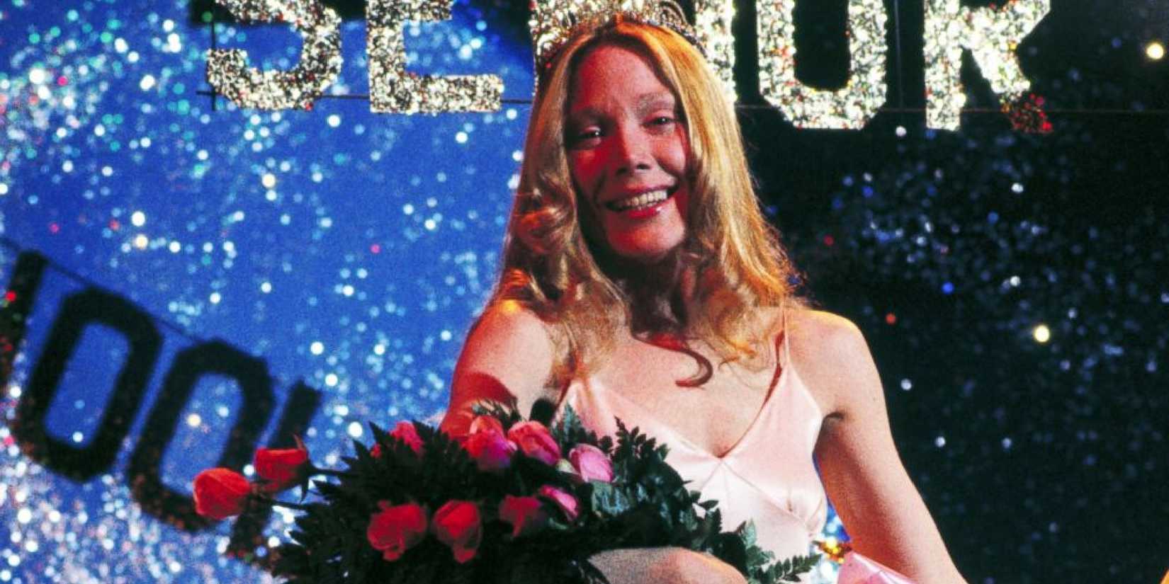 Carrie holding a rose bouquet and smiling while on stage in Carrie