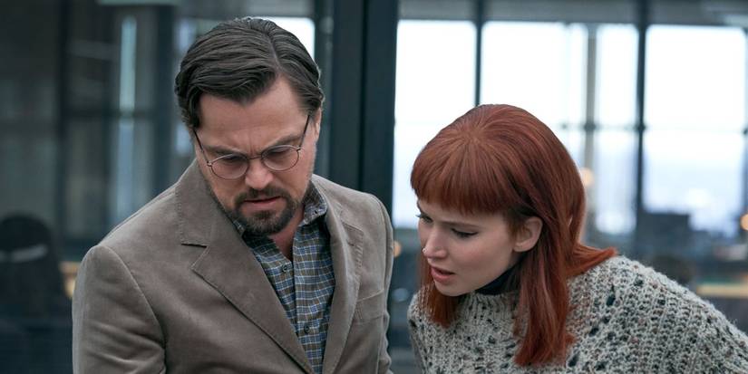Leonardo DiCaprio and Jennifer Lawrence looking down at something in Don't Look Up
