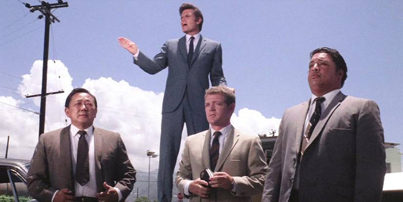 Steve McGarrett (Jack Lord) stands on top of a car as Dan Williams (James MacArthur), Kono Kalakaua (Gilbert Lani Kauhi), and Chin Ho (Kam Fong Chun) look onward on the original 'Hawaii Five-O'