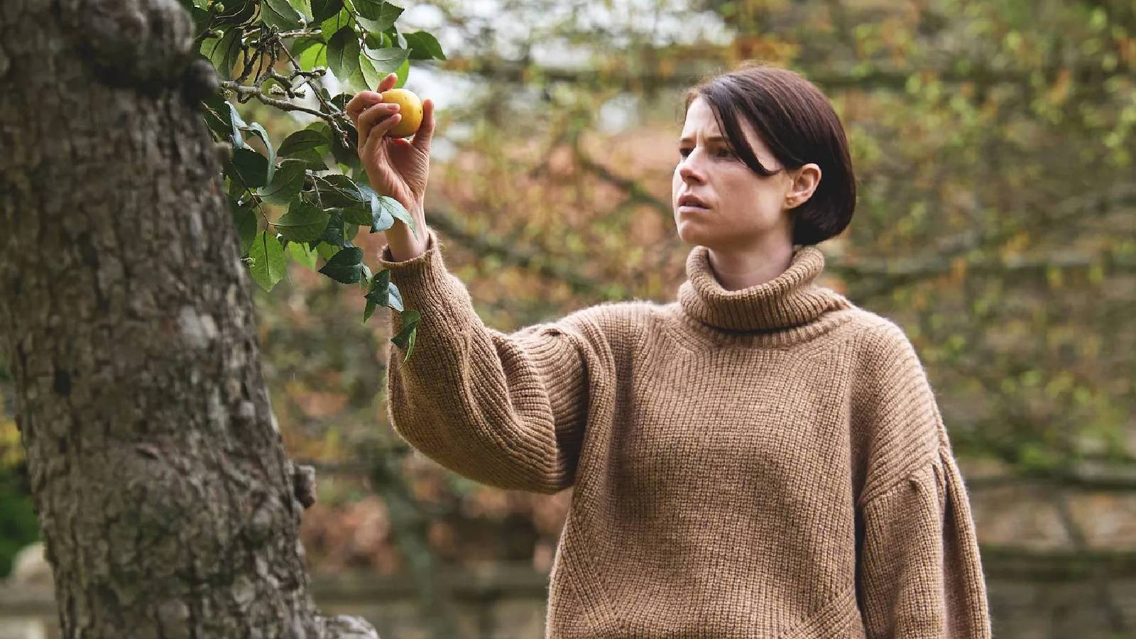 Harper holding a piece of fruit hanging from a tree in Men