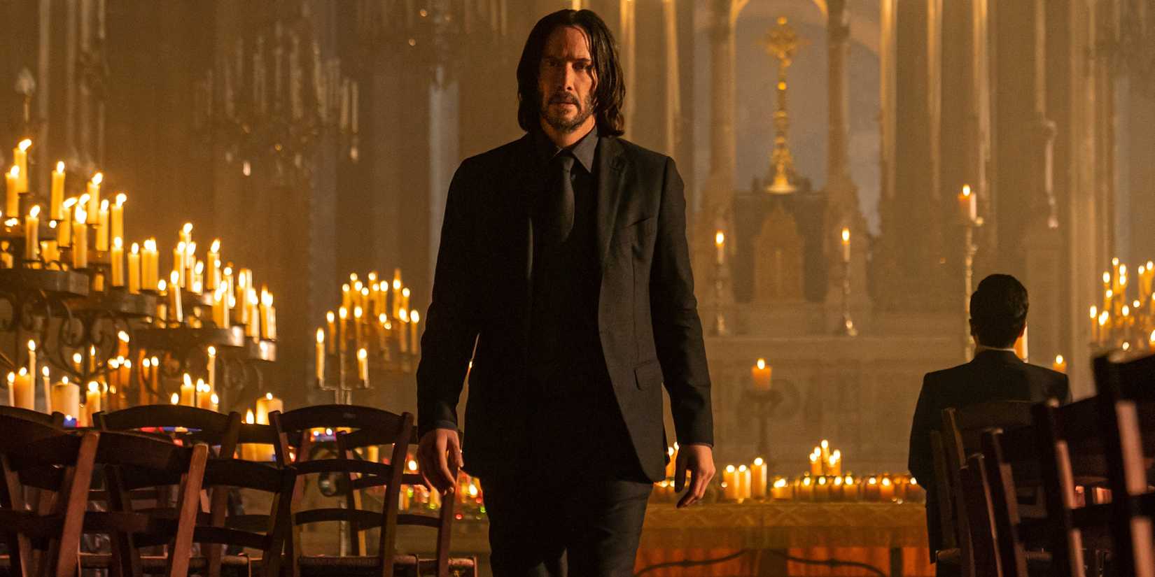 Keanu Reeves as John Wick walking in a Church lit by dozens of candles in 'John Wick: Chapter 4.'