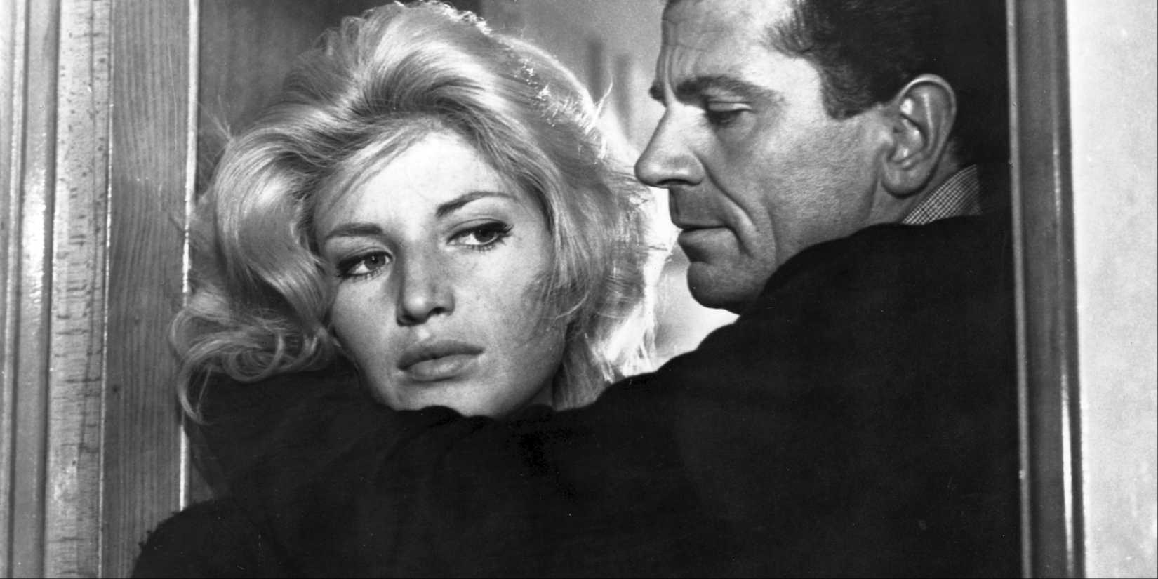 Monica Vitti and Gabriele Ferzetti embraced in a doorway in L'Avventura