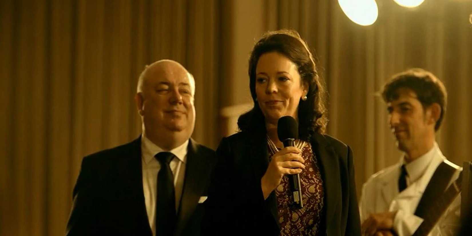 Olivia Colman holding a microphone and ready to make a speech in The Lobster