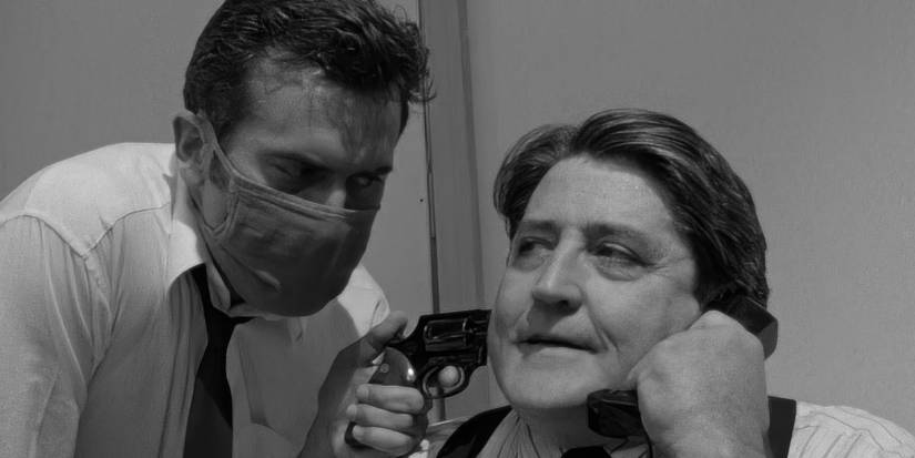 A man wearing a mask pointing a gun at another man on the phone in Running Time