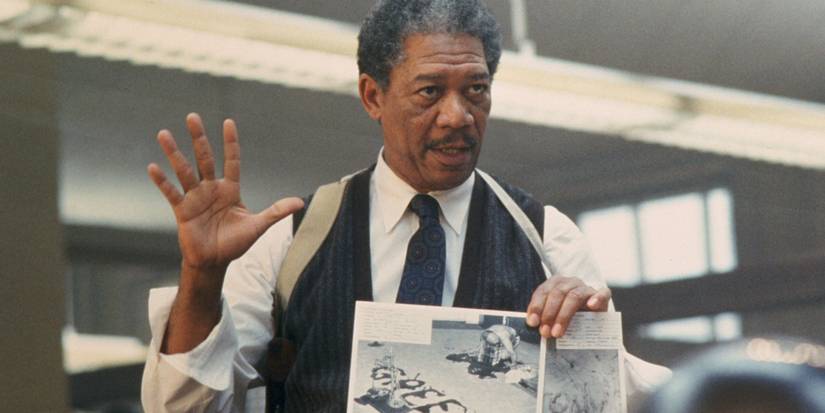 Morgan Freeman's Somerset holding his hand up while holding a crime scene photo in Se7en.