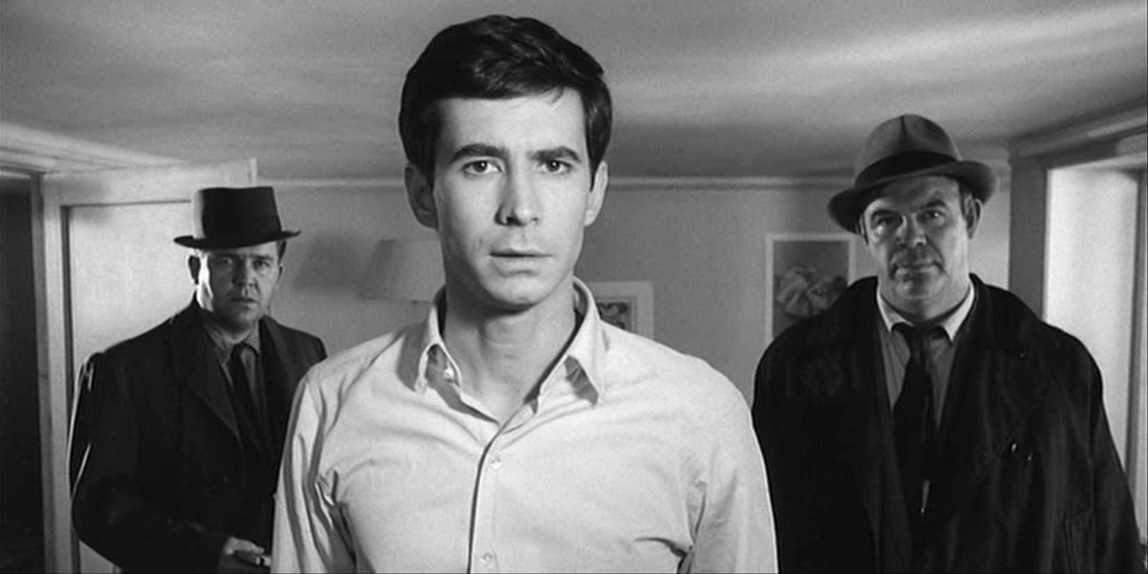 Três homens (incluindo Anthony Perkins) em uma sala parecendo intrigada no filme de Orson Welles, o julgamento