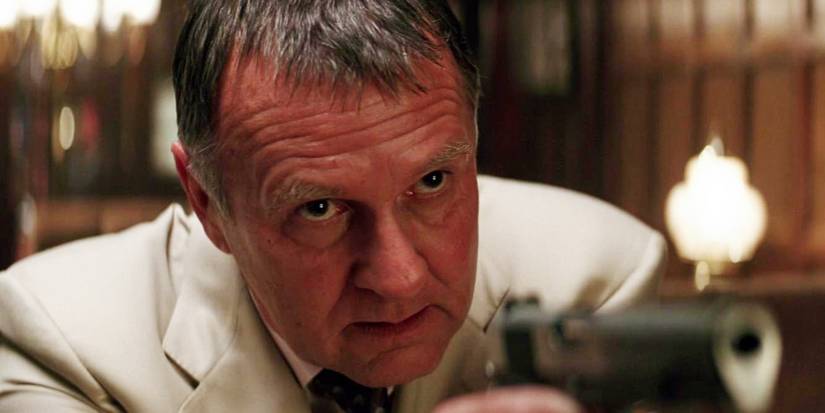 Tom Wilkinson as Carmine FAlcone in Batman Begins, holding a gun