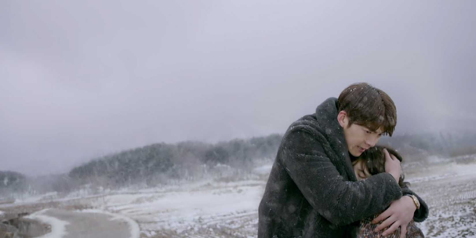 Two of the cast hold each other in a snowy landscape in Uncontrollably Fond. 