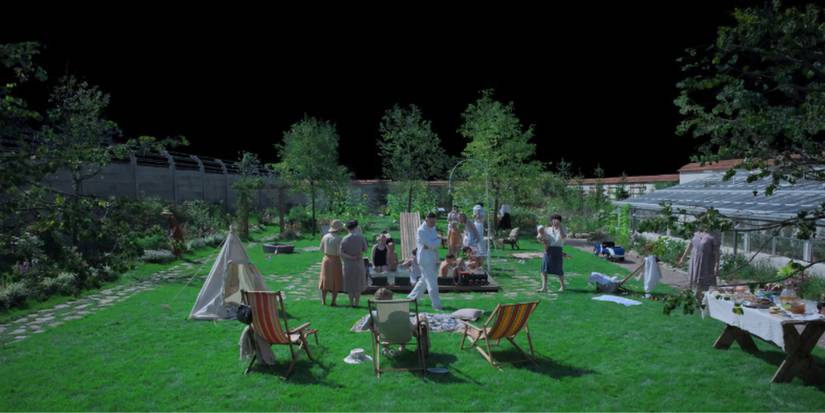 A group of people at a garden party against a black background in The Zone of Interest 