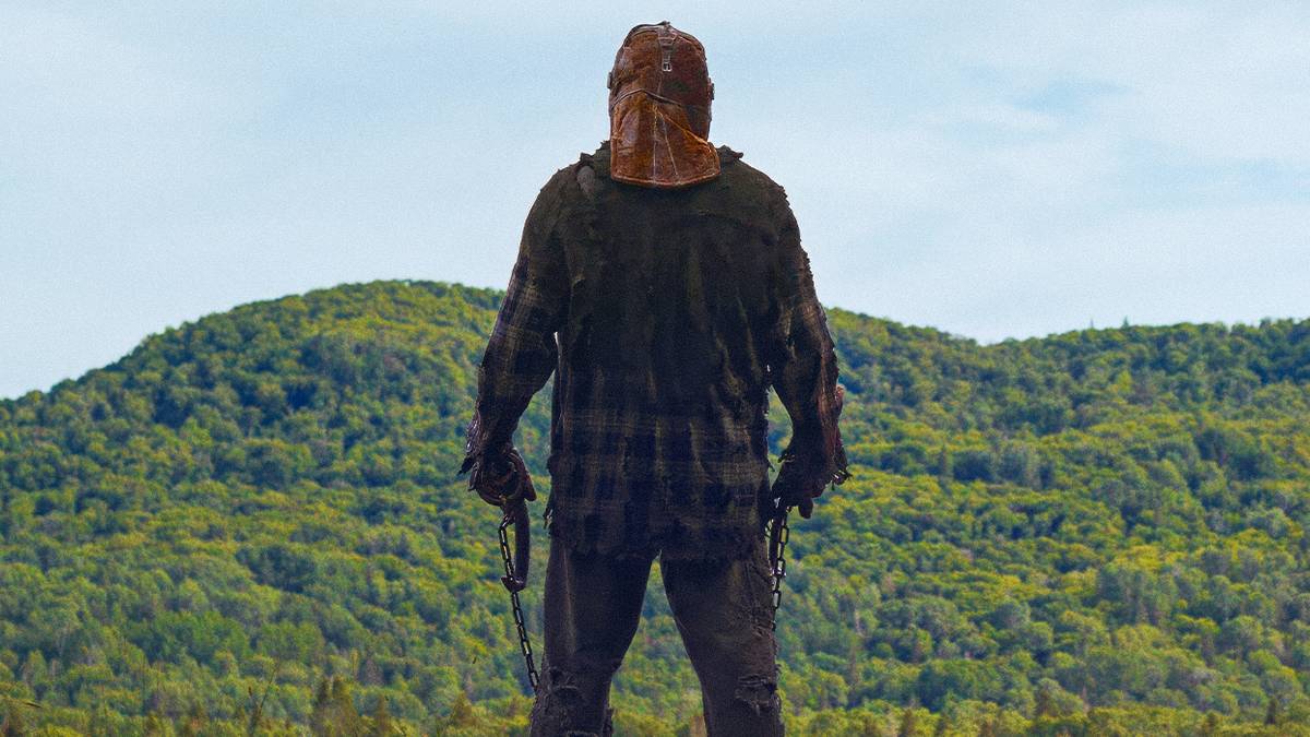 Ry Barrett as Johnny stands overlooking a ravine while holding his murderous weapons in In a Violent Nature
