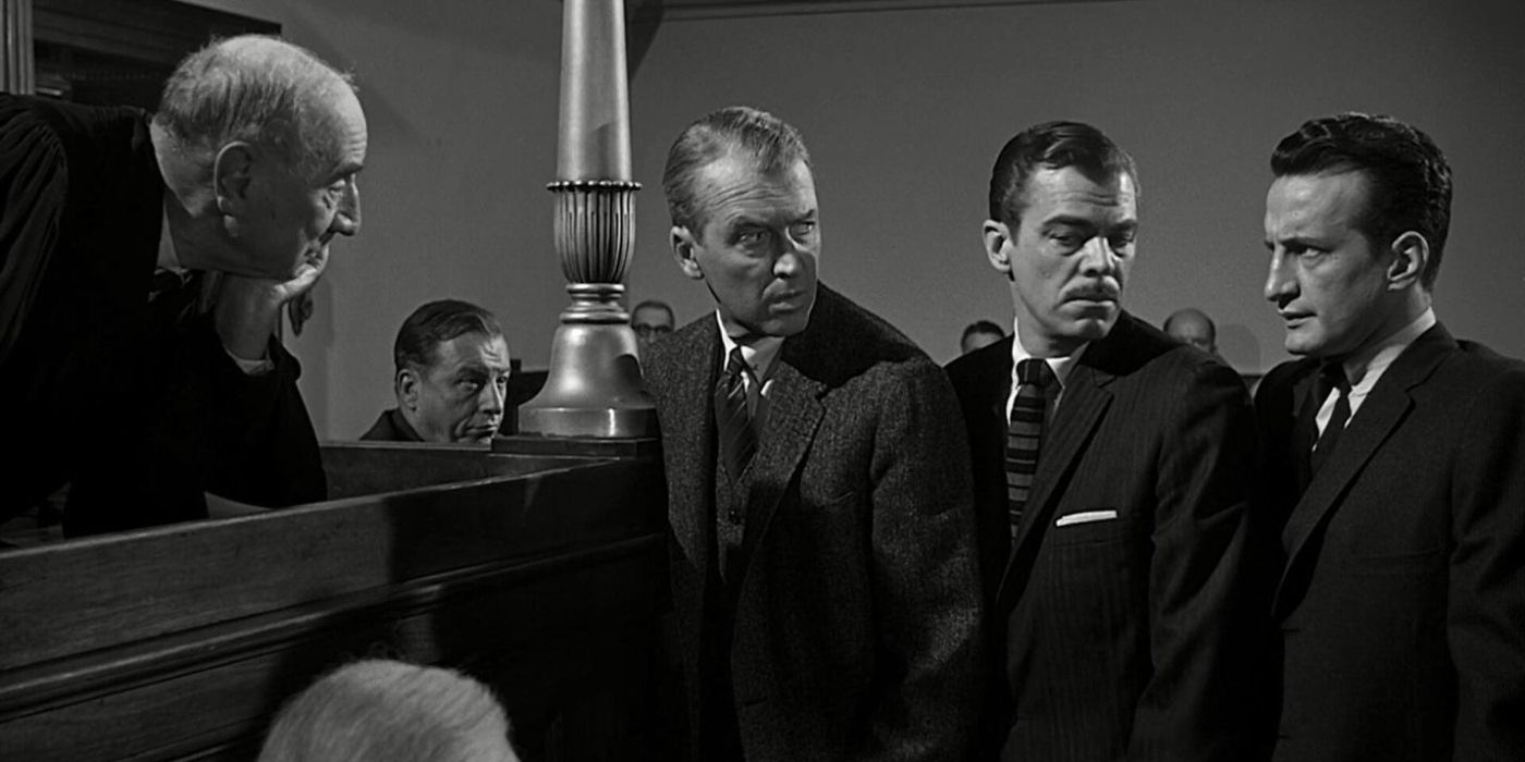 Paul Biegler, played by Jimmy Stewart, looking back at two prosecuting attorneys, played by Brooks West and George C. Scott, as they all stand at the judge's bench in Anatomy of a Murder