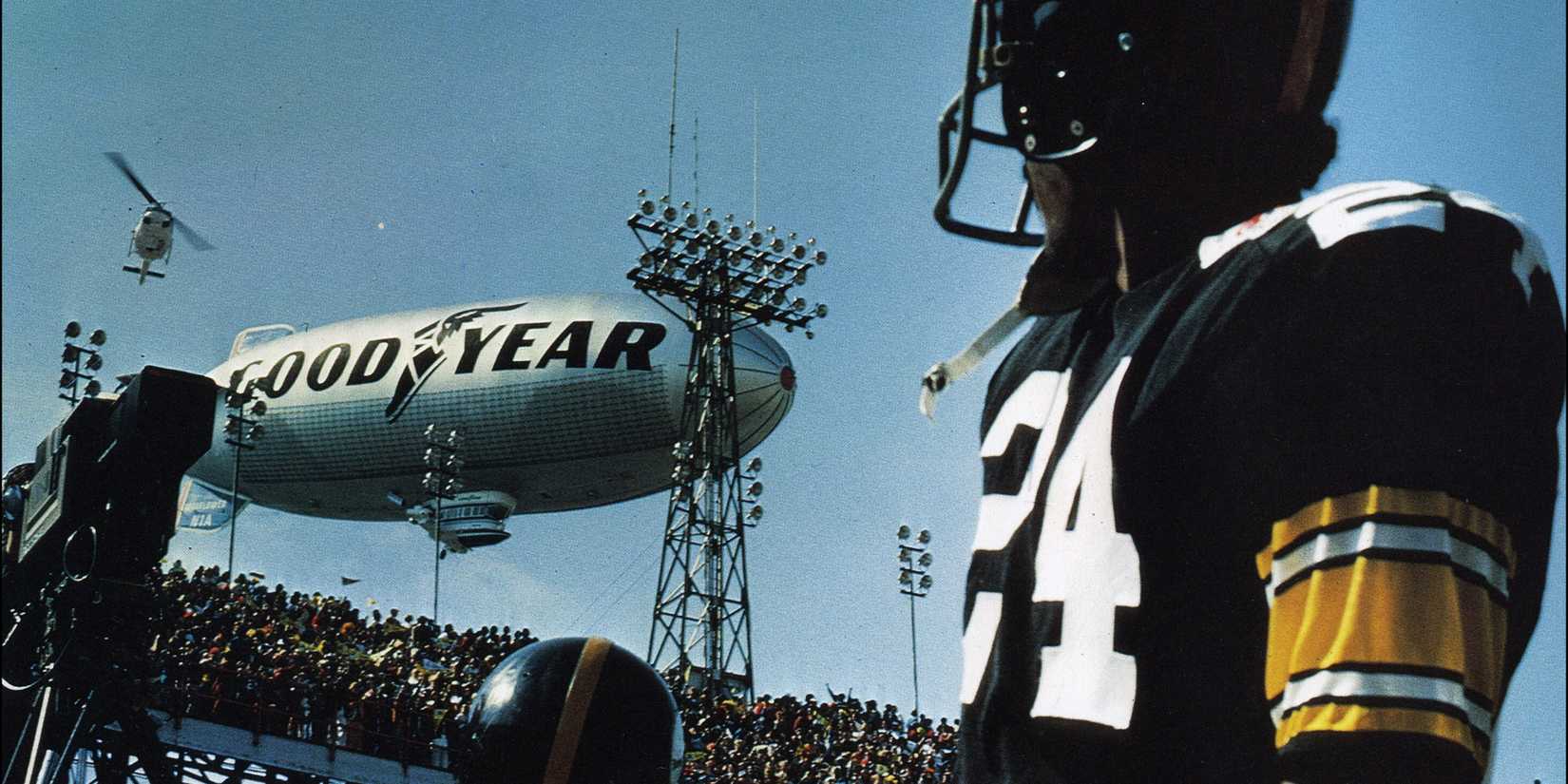 A football player looking up at a Goodyear blimp in Black Sunday