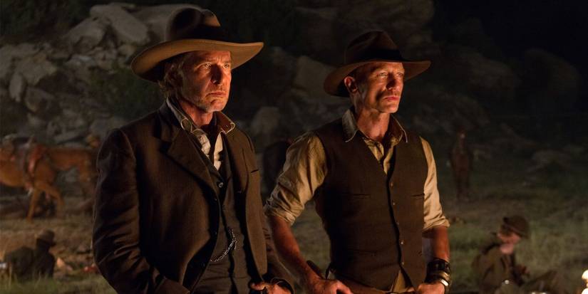 Harrison Ford and Daniel Craig in western apparel staring ahead outdoors at night in Cowboys & Aliens.