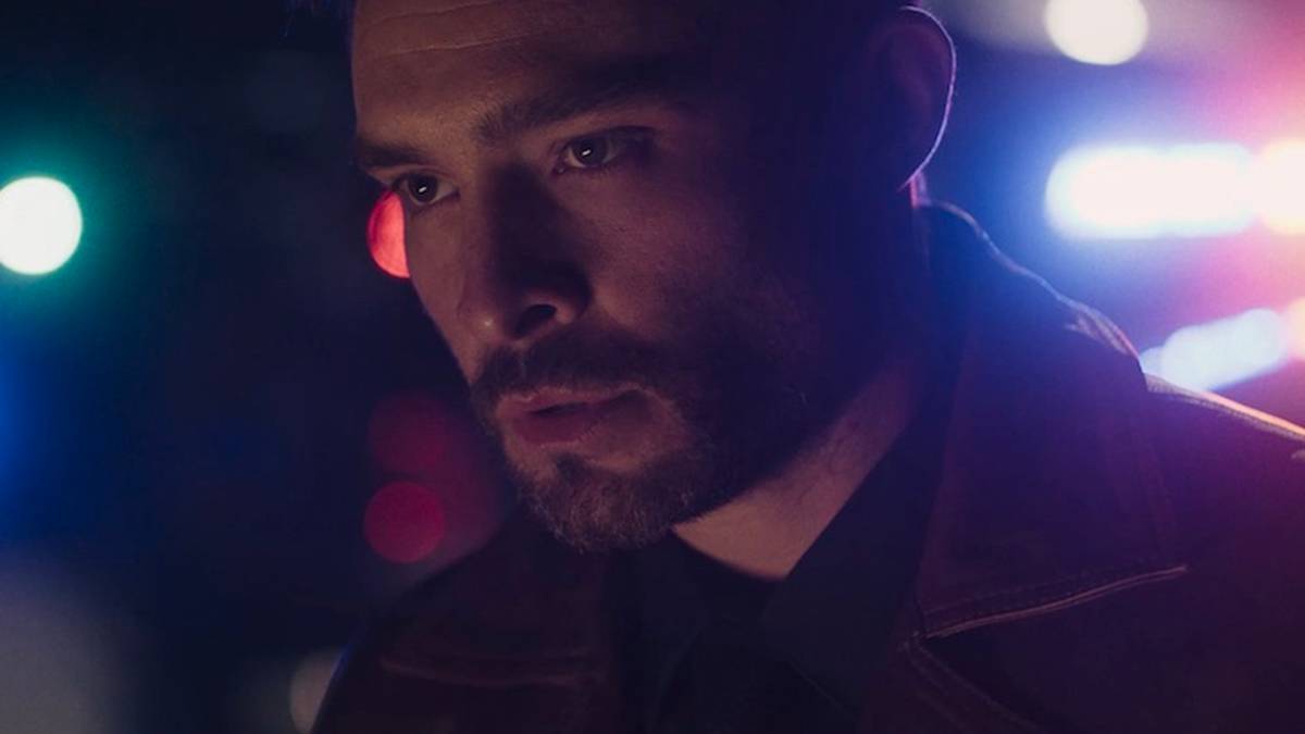 Ed Westwick in Dark Game, with police lights in the background